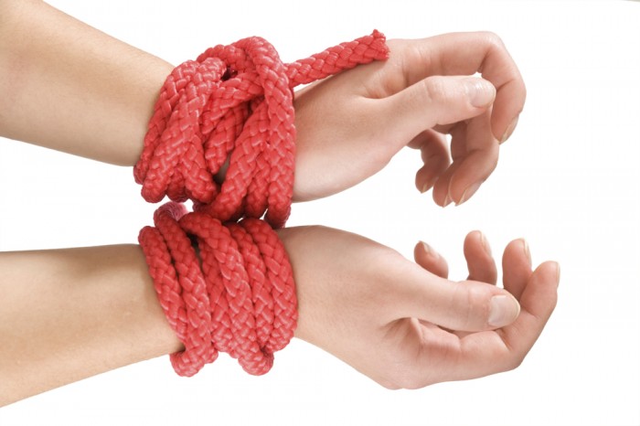 Female hands bound with red rope