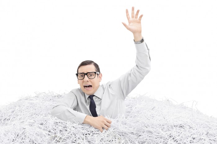 Helpless man drowning in a pile of shredded paper