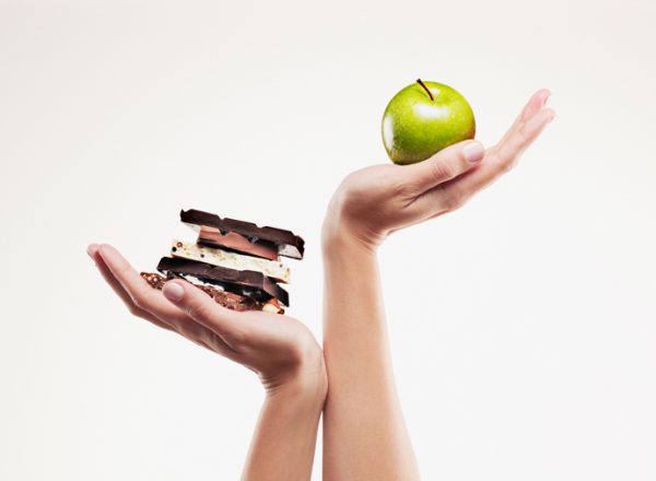 Woman cupping green apple above chocolate bars