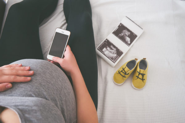 Young pregnant woman relaxing on sofa with smart phone