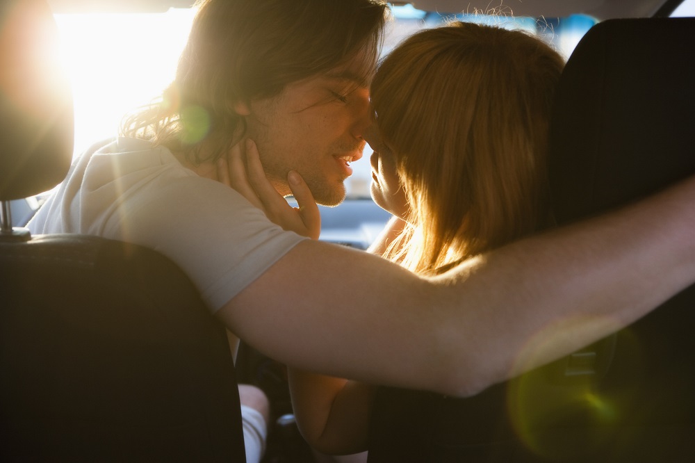 Man kissing woman in car