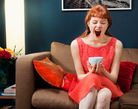 Woman sitting on sofa, yawning.