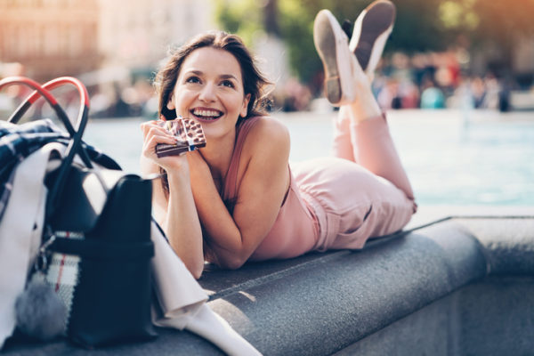 Young woman lying down in the park and eating chocolate