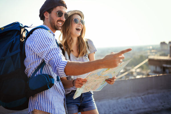 Happy young couple of travellers holding map in hands