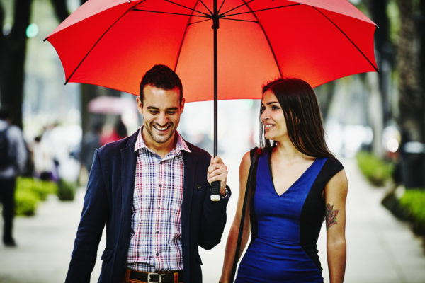 Smiling couple walking under umbrella