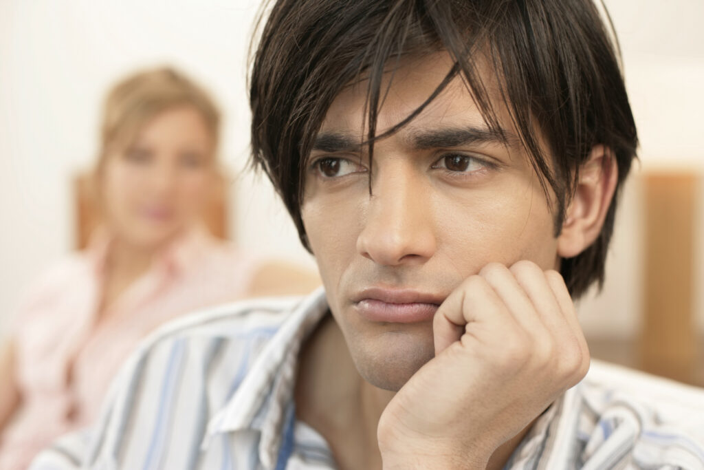 Dissatisfied young man, woman sitting in background