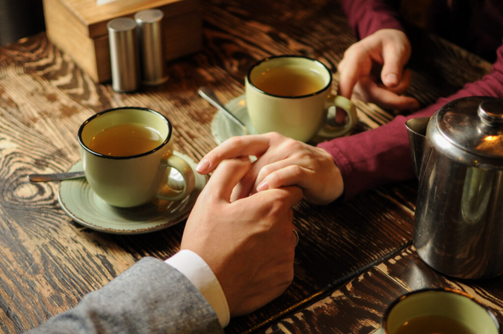 Young couple dating, drinking tea and holding hands in a cafe in cold weather.