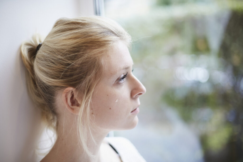 Young woman crying at the window