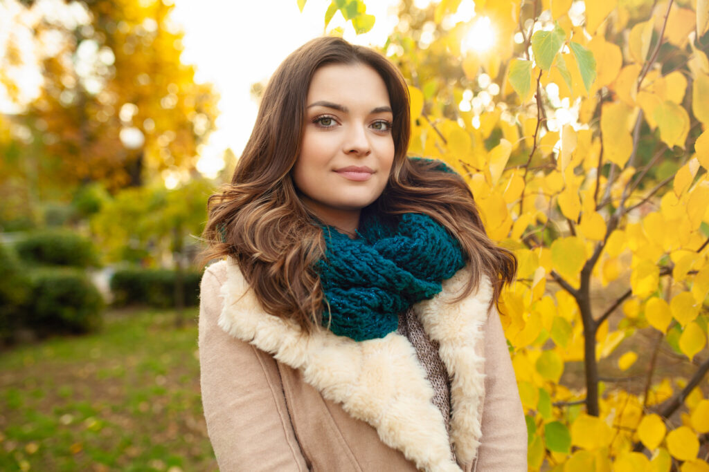 A beautiful young girl walks through the autumn park on the background of brightly colored leaves
