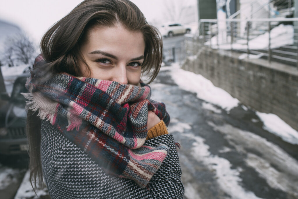 Portrait confident young woman in plaid scarf on snowy winter street