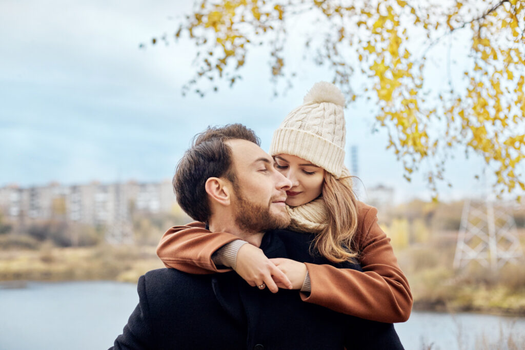 Loving couple walking in Park in autumn hugs and kisses. Autumn walk men and women in the woods on the fallen leaves. Romance and love on an autumn landscape