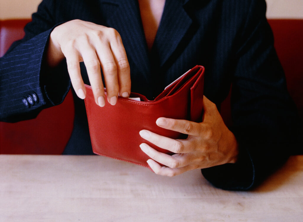 Businesswoman Opening Red Wallet at Table