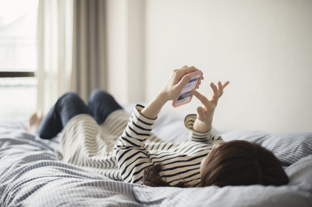 Woman using the smartphone on bed