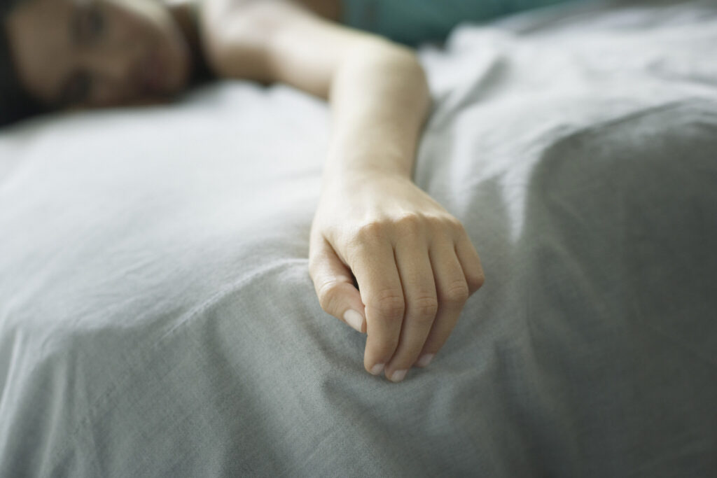 Woman lying on bed relaxing focussing on her hand