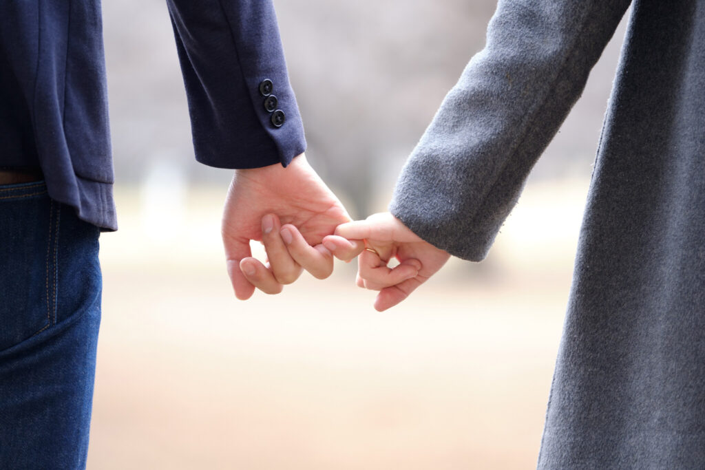 A Japanese man and woman holding hands in a park in winter