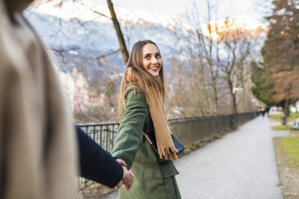 Austria, Innsbruck, portrait of happy young woman strolling hand in hand with her boyfriend at winter time