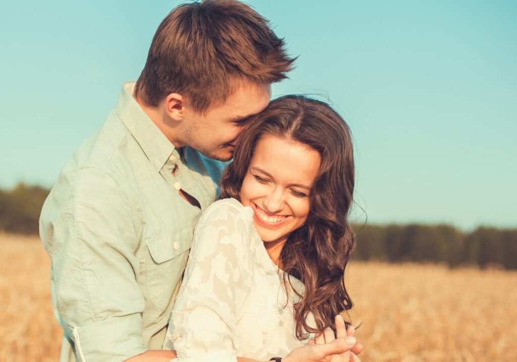 Young couple in love outdoor. Stunning sensual outdoor portrait of young stylish fashion couple hugging and smiling in summer in field