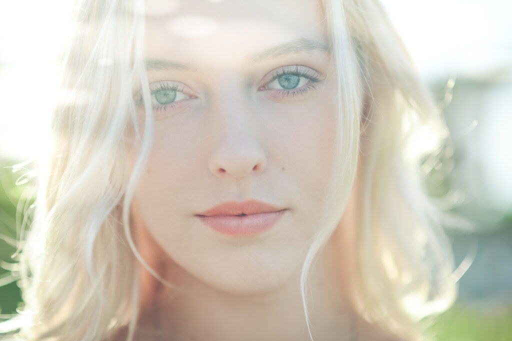 Summer headshot of beautiful young blonde woman with sunflare