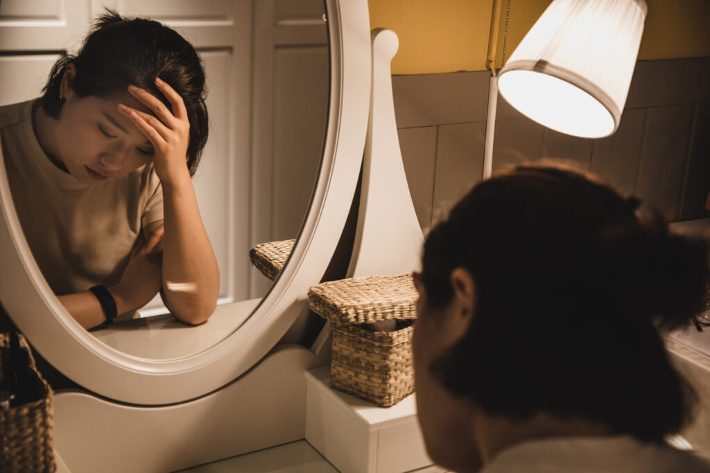 Asian woman sitting in front of the dressing table feeling depressed