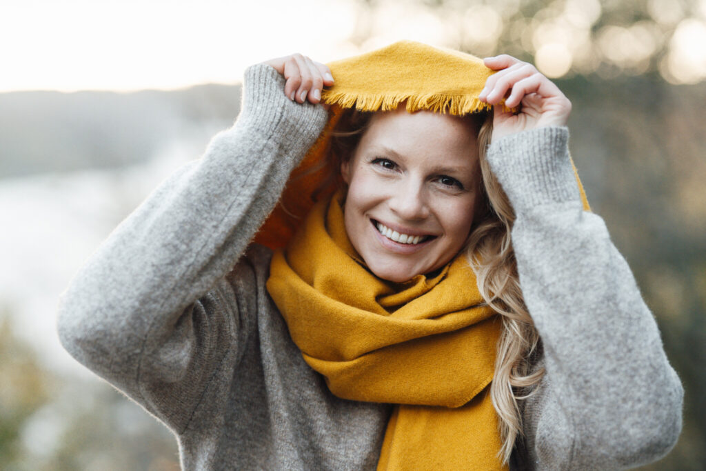 Woman smiling while holding yellow scarf