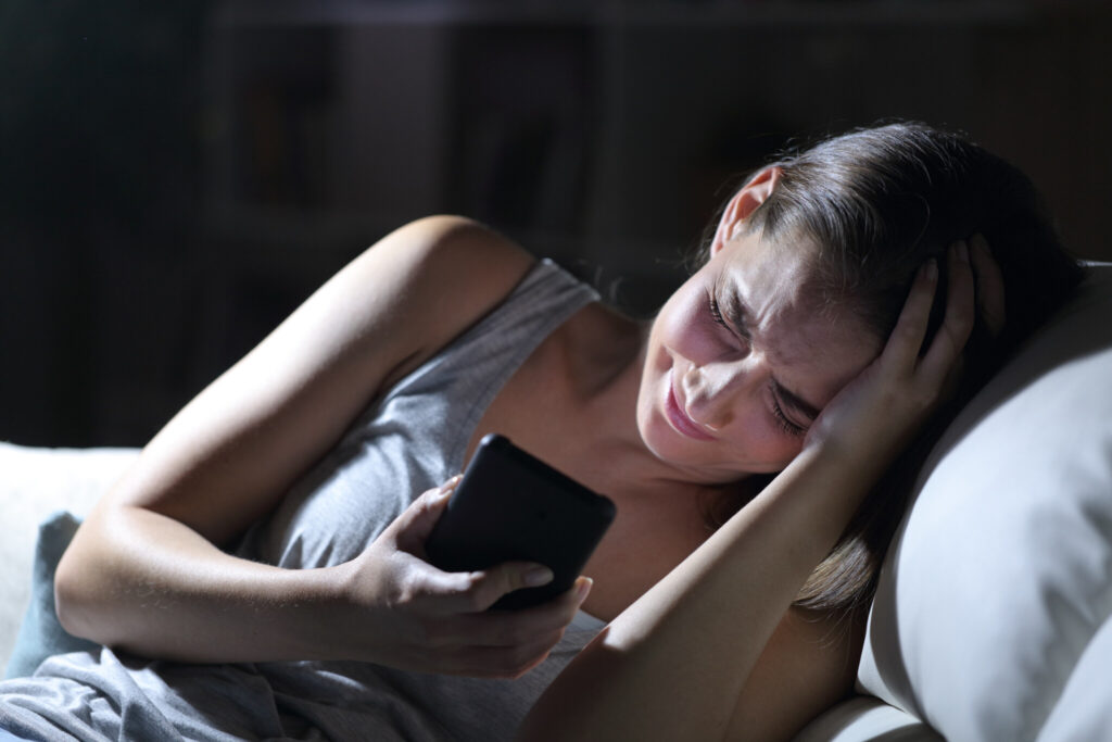Sad woman complaining with phone at night at home