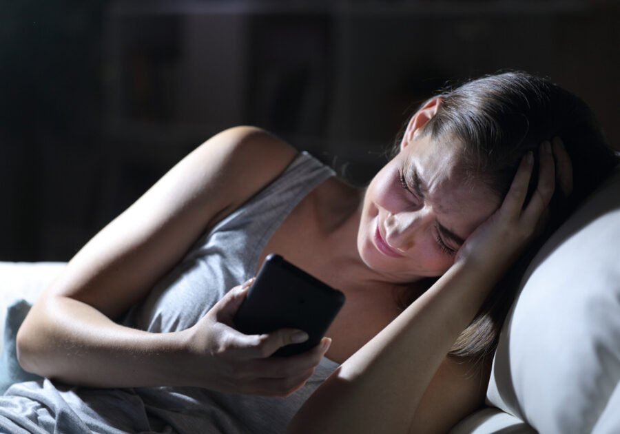 Sad woman complaining with phone at night at home