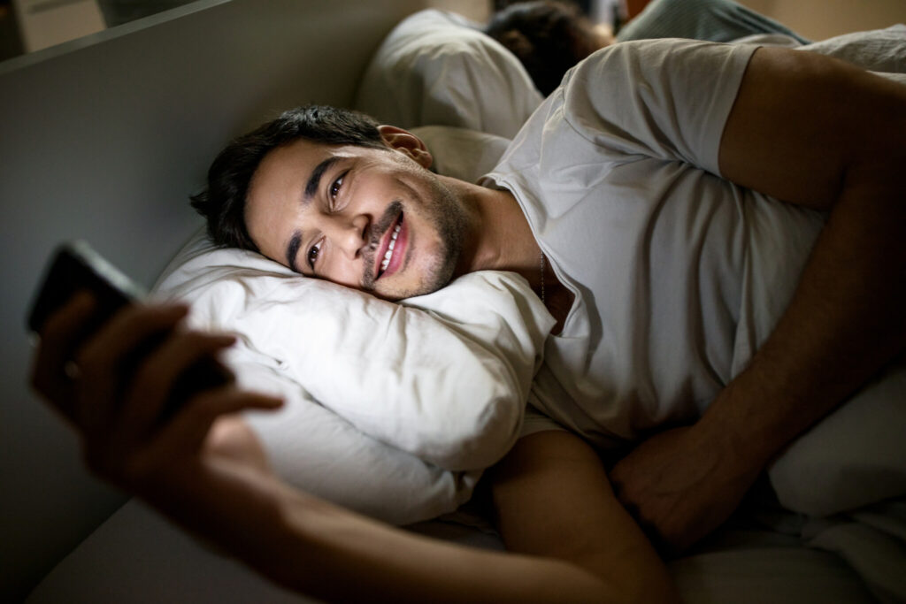 Man in bed using mobile phone