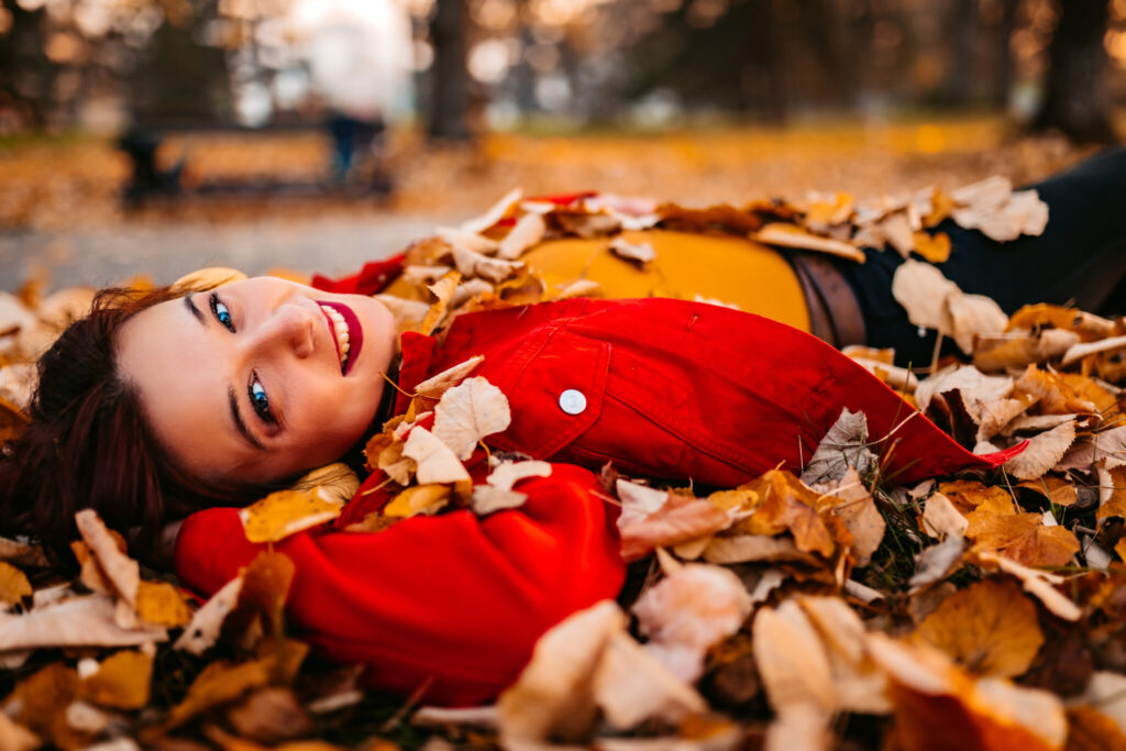 Young Woman Lying On Autumn Leaves