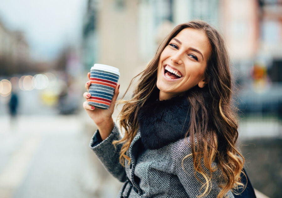 Young woman with coffee cup smiling outdoors