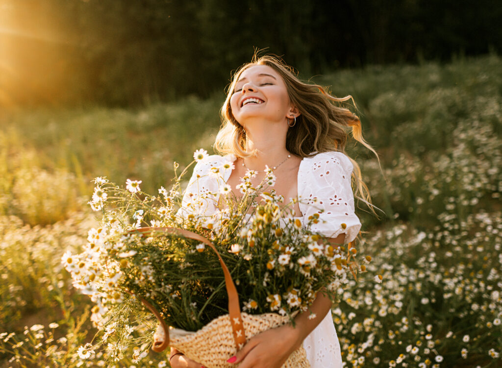 Young adult woman outdoors in camomile field enjoying summer