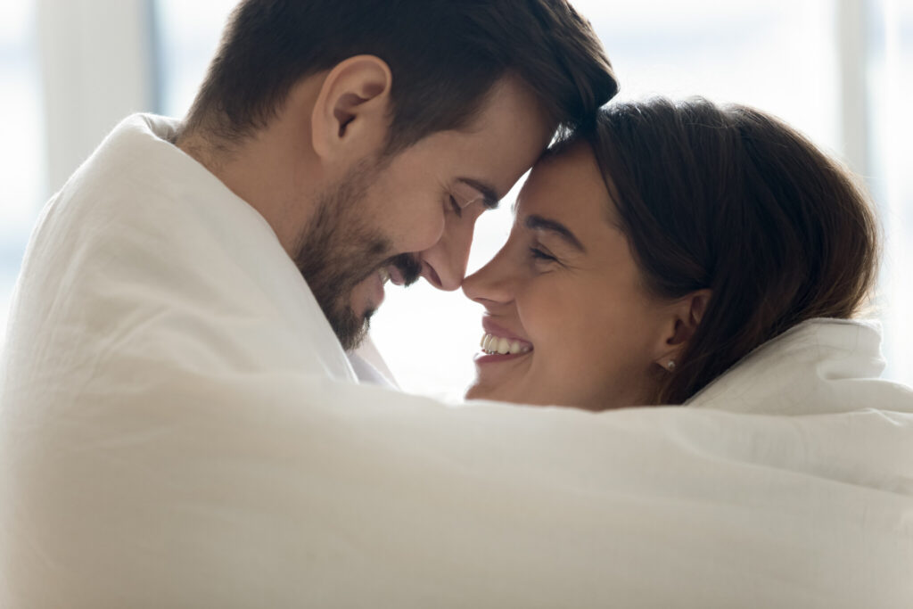 Mixed race couple cuddling touch foreheads covered in warm blanket