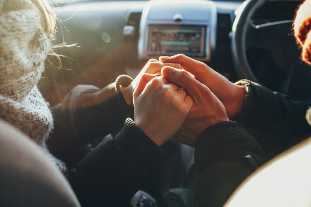 Cropped image of couple holding hands in car