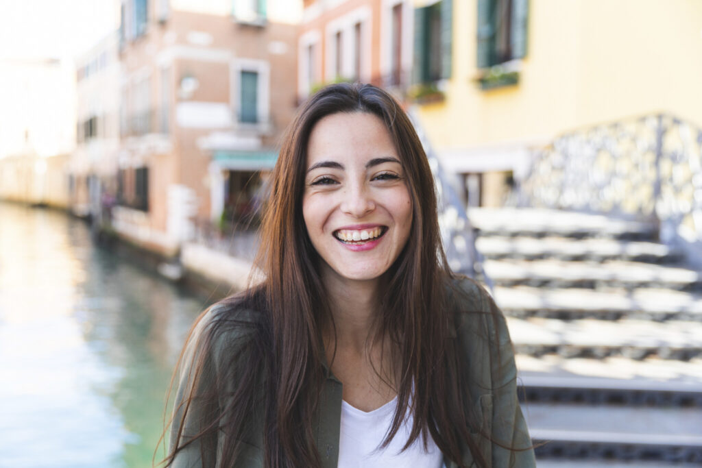 Italy, Venice, portrait of laughing young woman in the city with canal in background