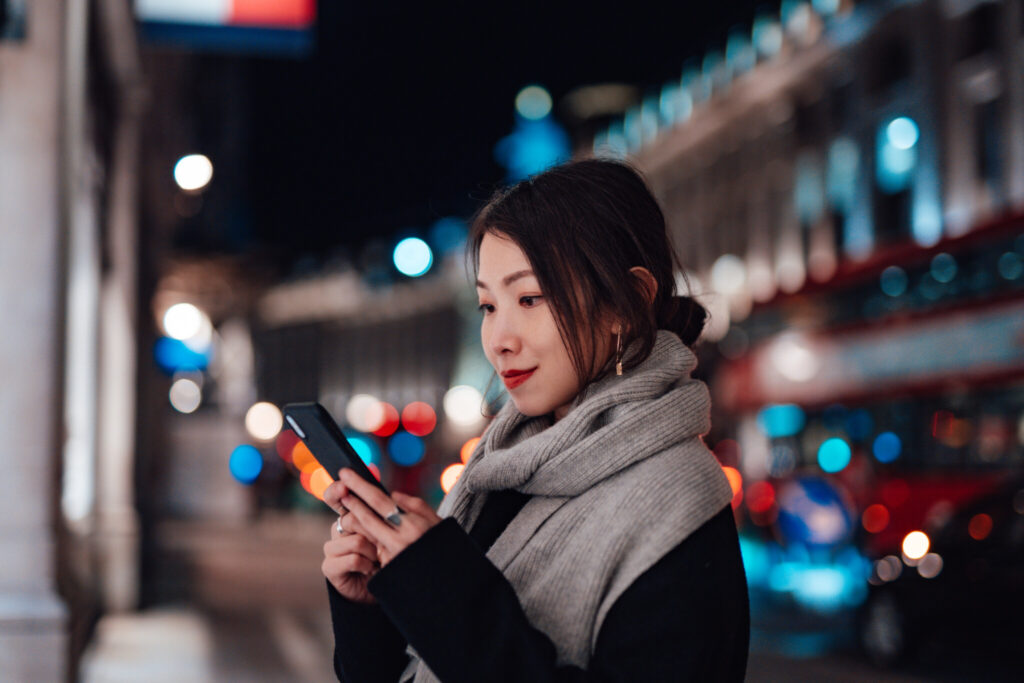 Young Woman Using Smartphone On The City Street At Night