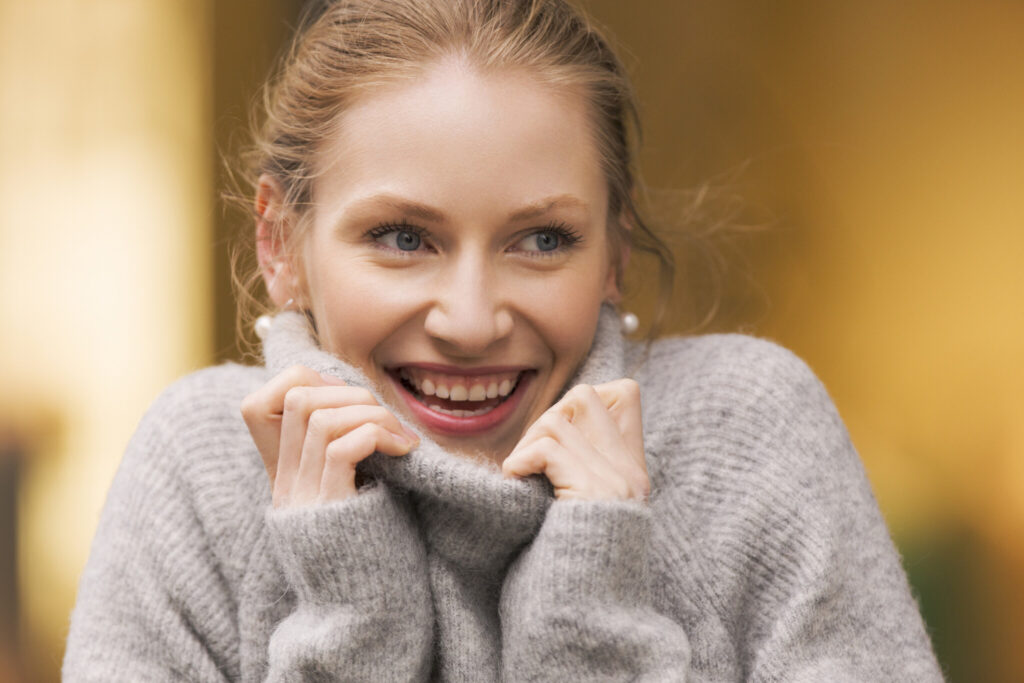 blond woman holding her wool pullover’s collar up