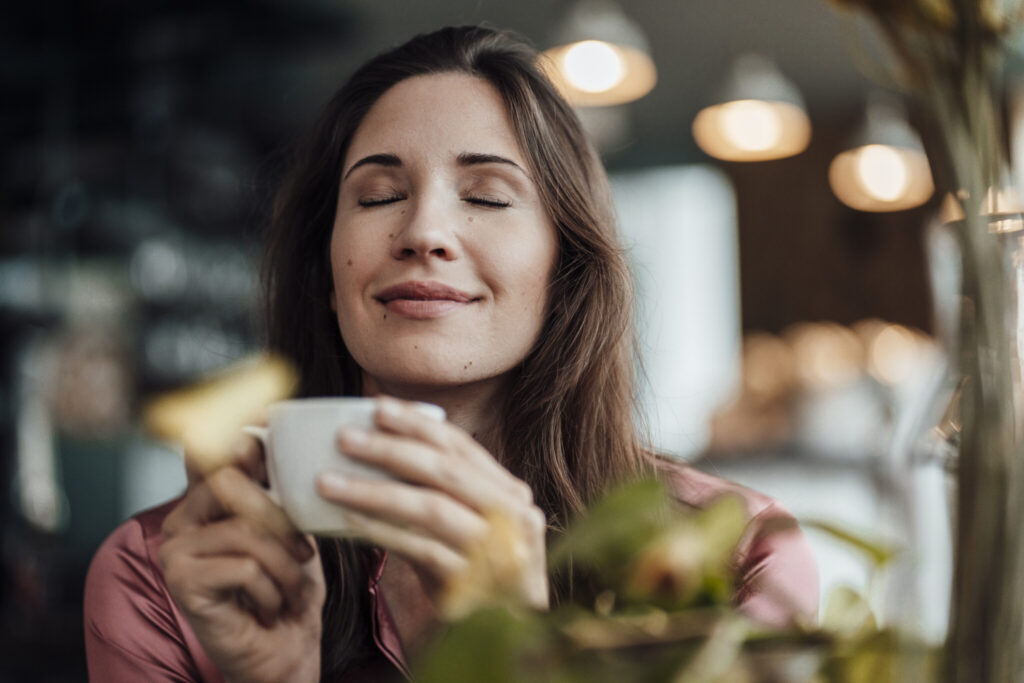 Smiling businesswoman smelling coffee in cafe