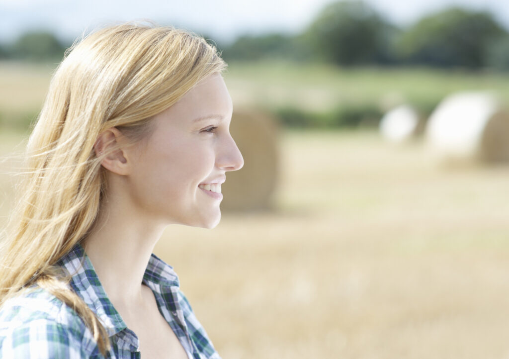 Profile of woman in countryside with bails of hay.