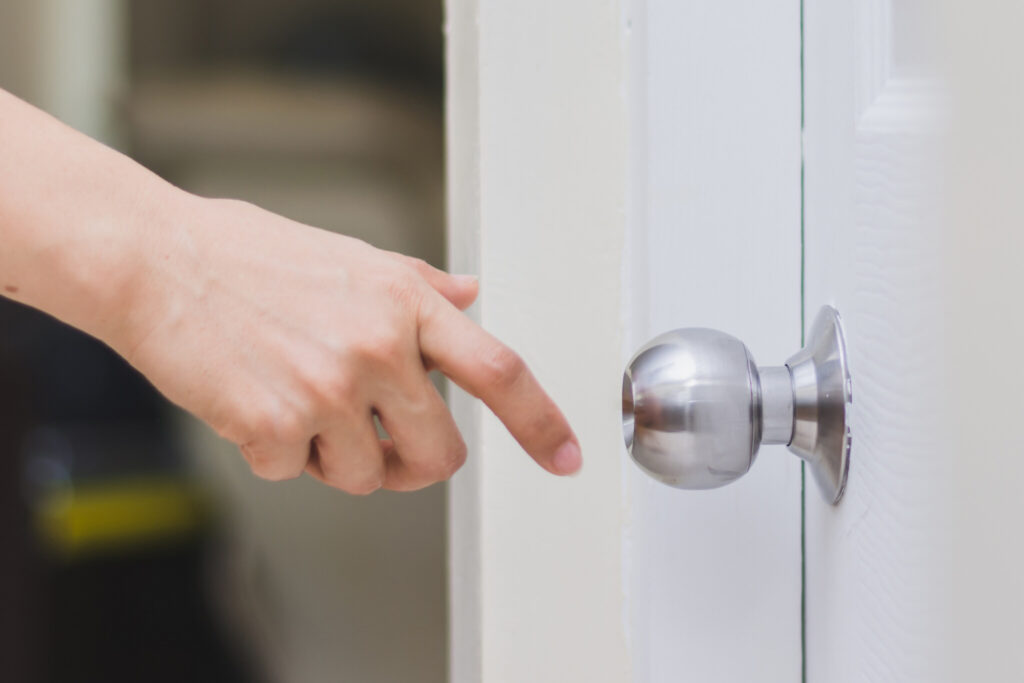 close up of woman’s hand reaching to door knob, opening the door