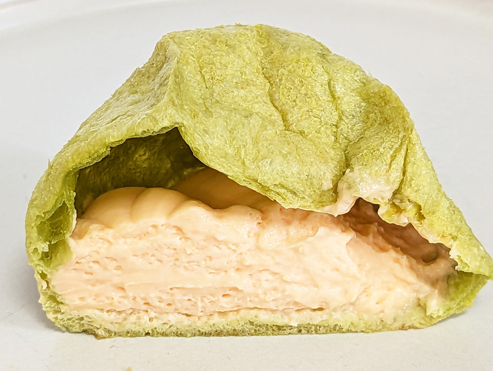 生地が薄緑色のシュークリームの断面図　赤肉メロンクリームのメロンもこの断面図