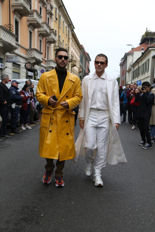白のセットアップを着た男性と、マスタードカラーのコートを着た男性