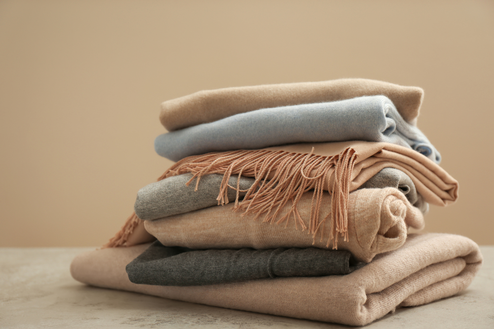 Stack,Of,Cashmere,Clothes,On,Stone,Table