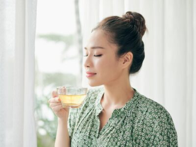 women standing in front of windows and holding tea cup in the morning