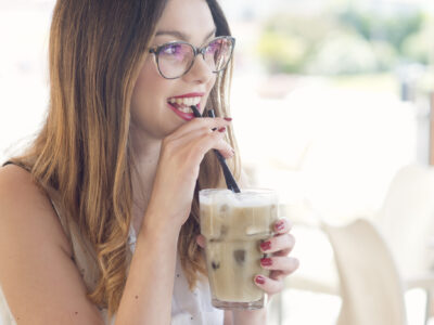 Beautiful, young woman sitting at the open air bar and enjoying iced coffee.